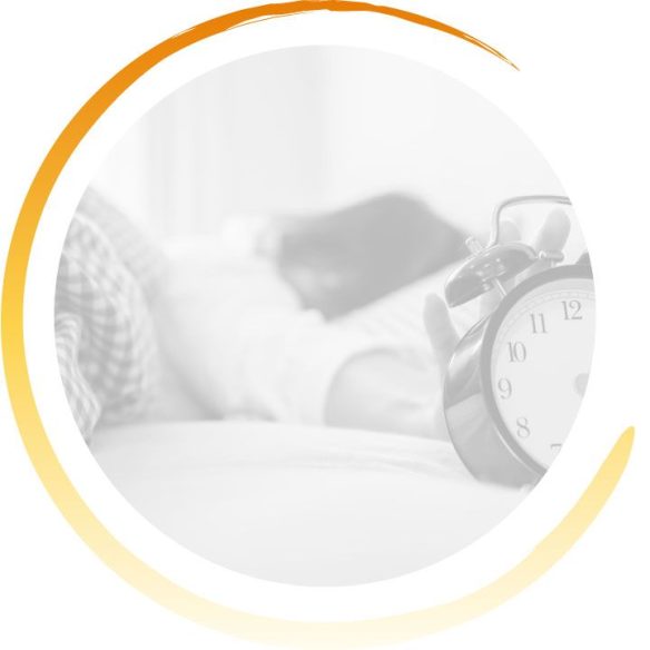 Femme couchée dans son lit qui tend la main vers son réveil